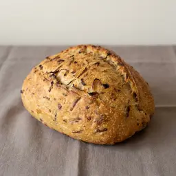 Hagymás kenyér cipó, a héjában látszanak a pirított hagymadarabok.